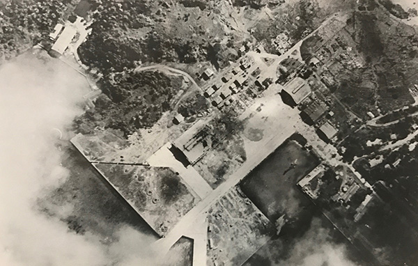 A black-and-white aerial photograph from 1944 showing the area before development. Runways and facilities are visible along the coastline, surrounded by largely undeveloped land and natural areas, illustrating land use conditions prior to later development.
